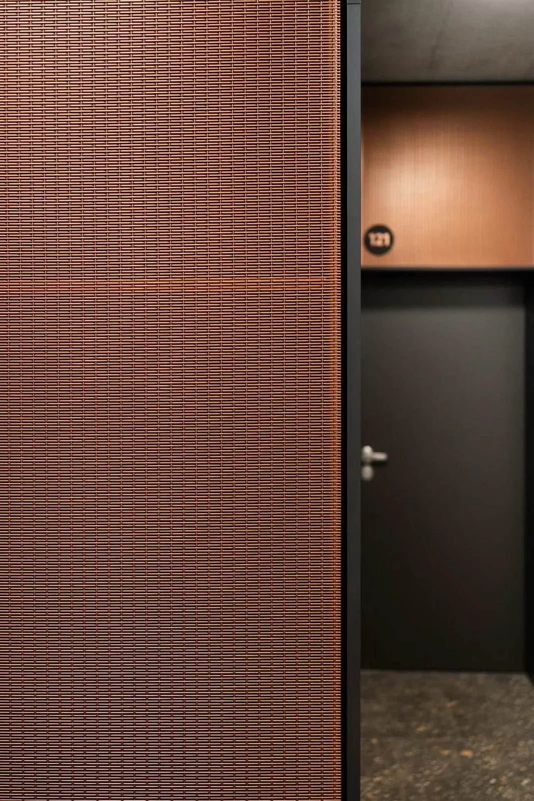 Copper-toned architectural metal mesh wall cladding with framed edge detail